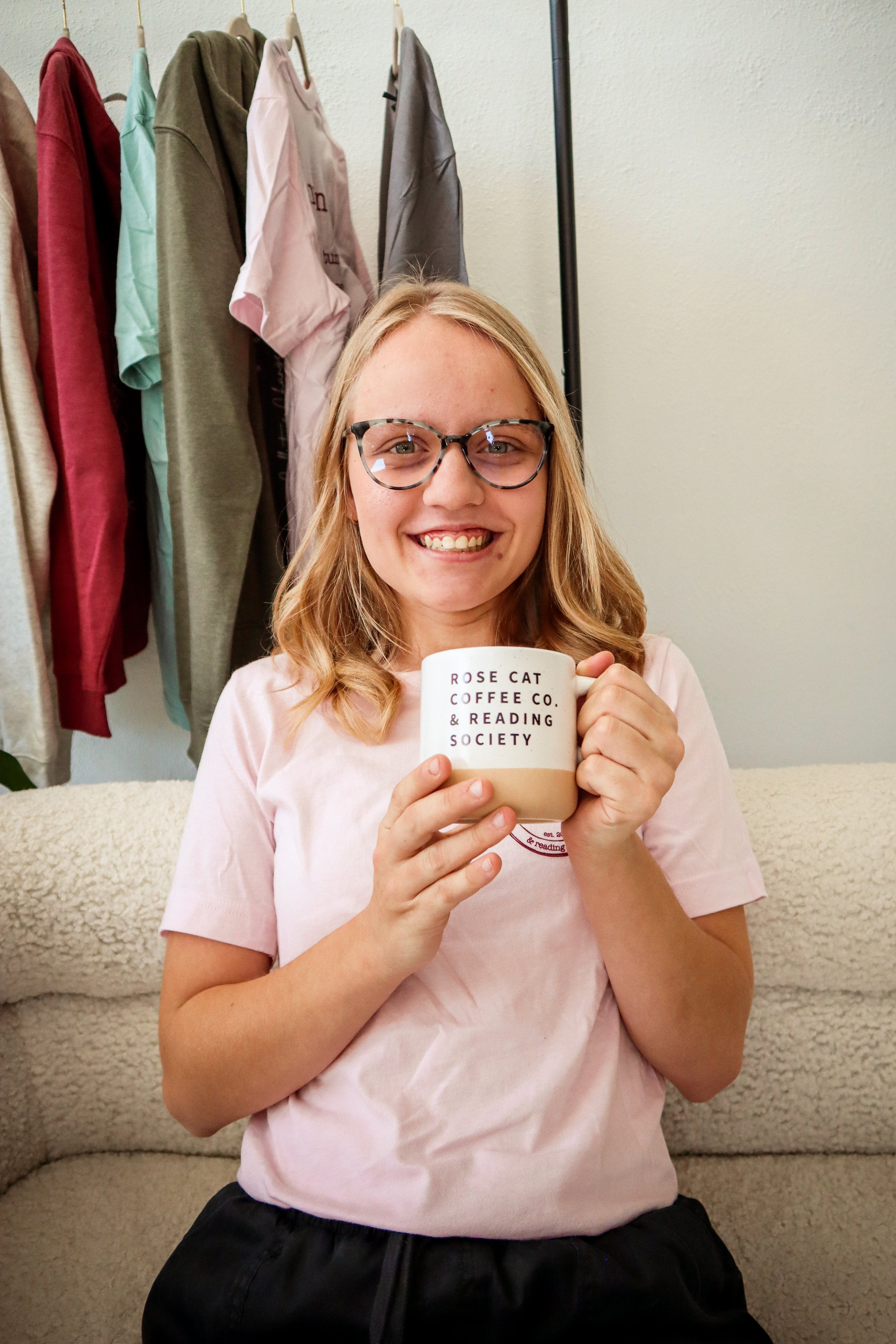 Barista at Rose Cat Coffee Co, Aubrey, posing with a Rose Cat Coffee mug, available in store or online. 