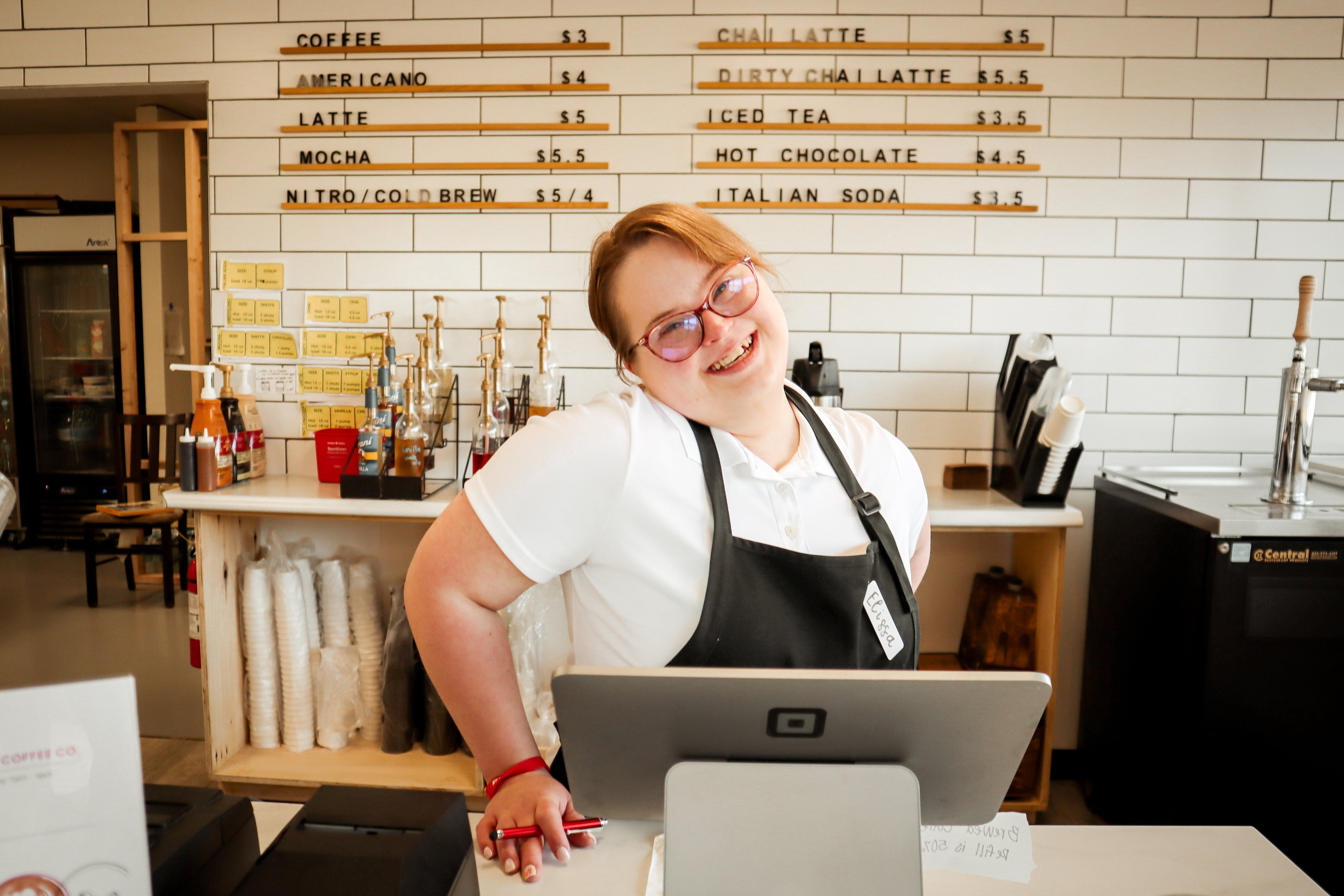 Rose Cat Coffee Co Barista, Elissa, poses behind the counter with a smile on her face!