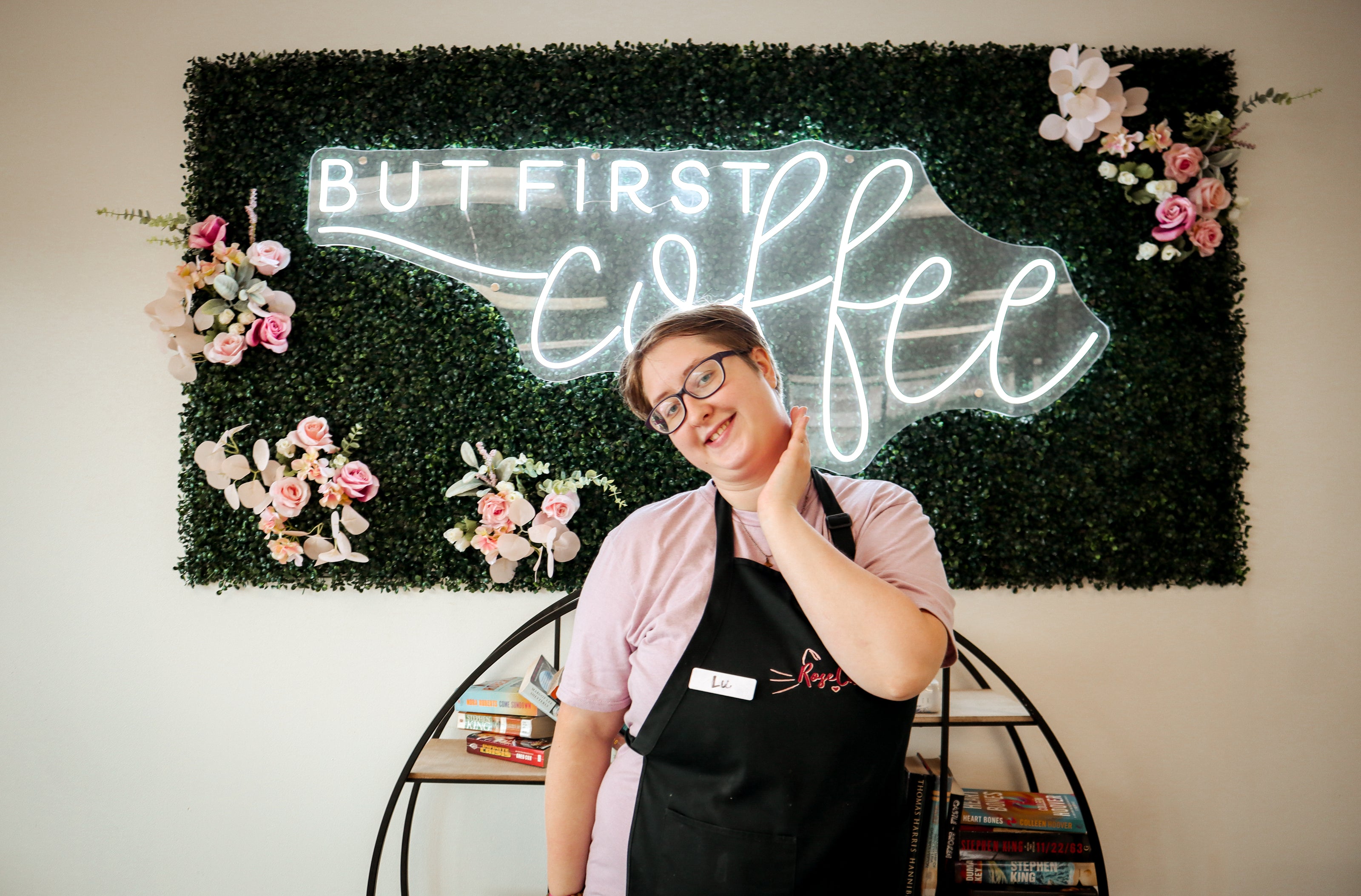 Rose Cat Barista, Lu, poses in front of decor in the coffee shop.